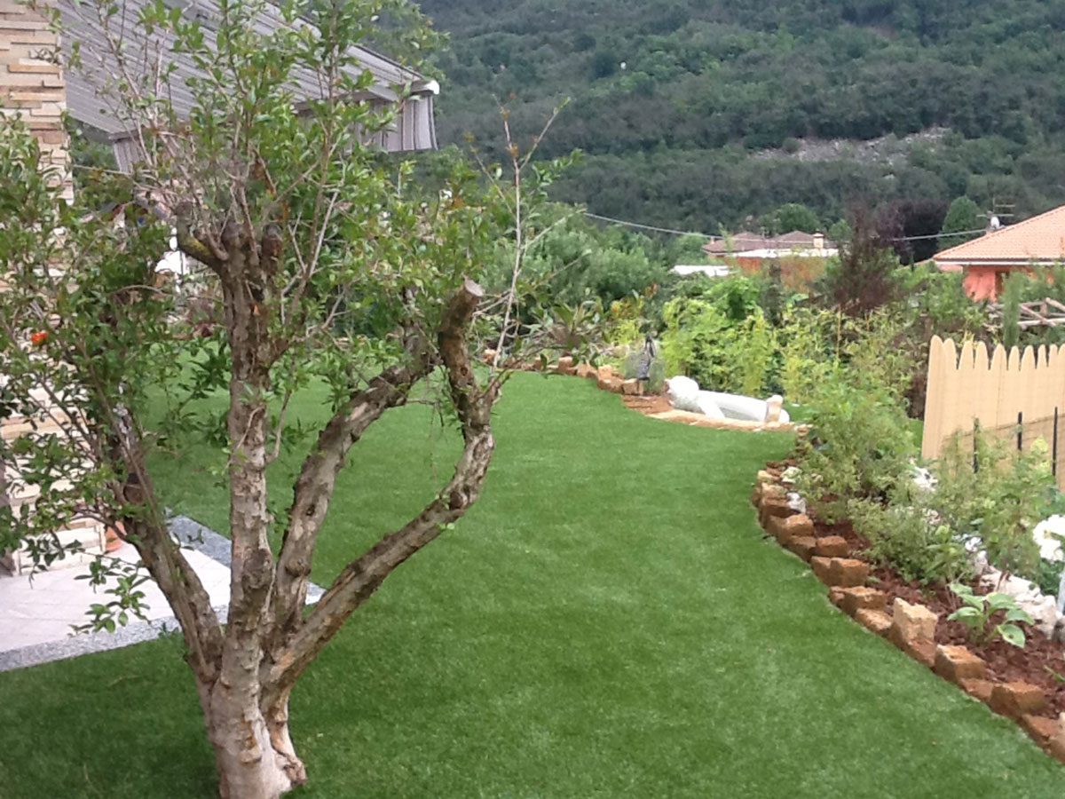 Parco di un hotel a Omegna, realizzato da Lucon con parti in erba sintetica che si itnegrano con verde naturale e ulivi